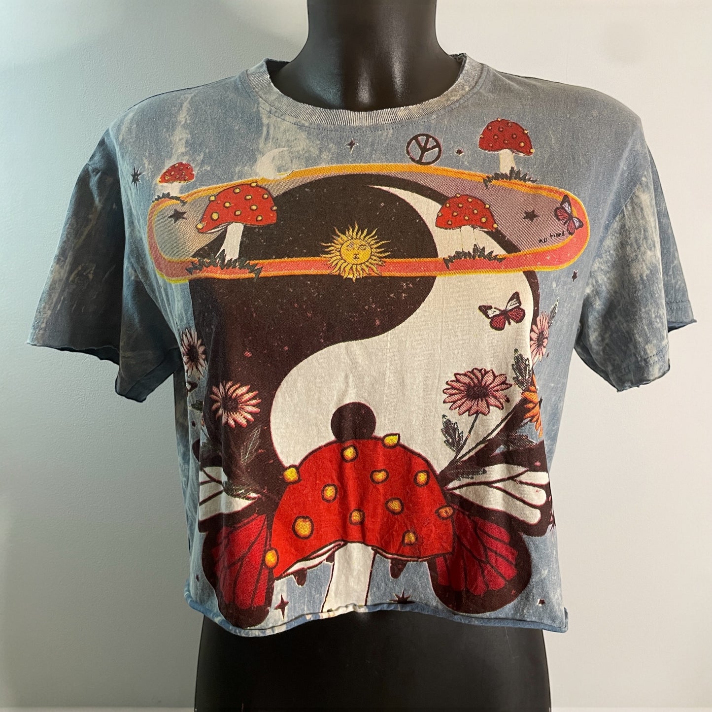 Crop top da donna blu vintage in cotone con grafica hippie psichedelica: simbolo Yin Yang decorato con funghi rossi, fiori e farfalle, model.