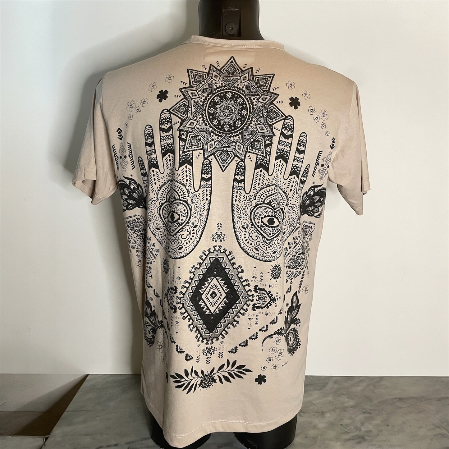 Maglietta unisex beige con grande stampa Hamsa boho: mani decorate, motivi geometrici e dettagli bianco e nero, back on model.