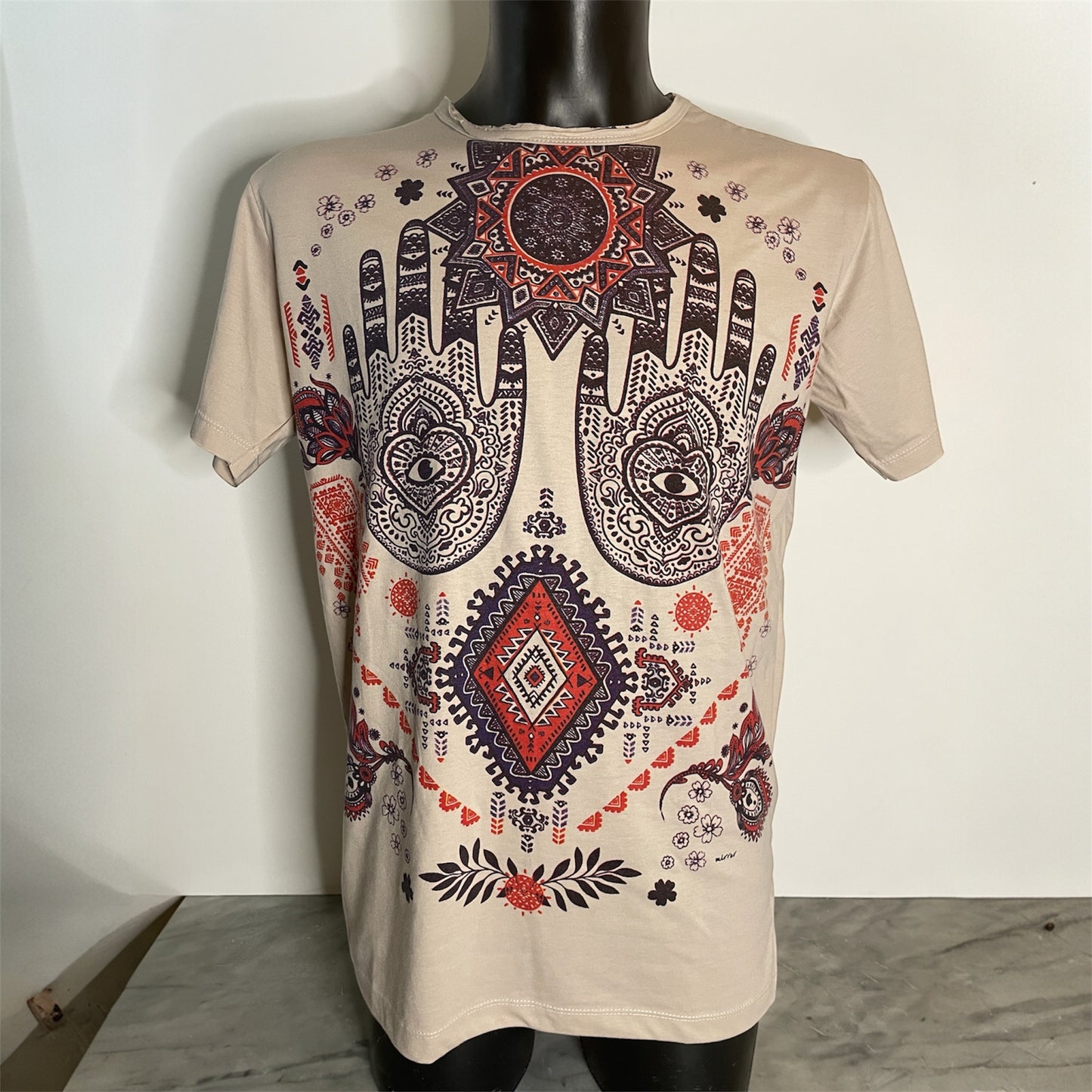 Maglietta unisex beige con grande stampa frontale Hamsa boho: mani decorate, motivi geometrici e dettagli rossi e neri, on model.