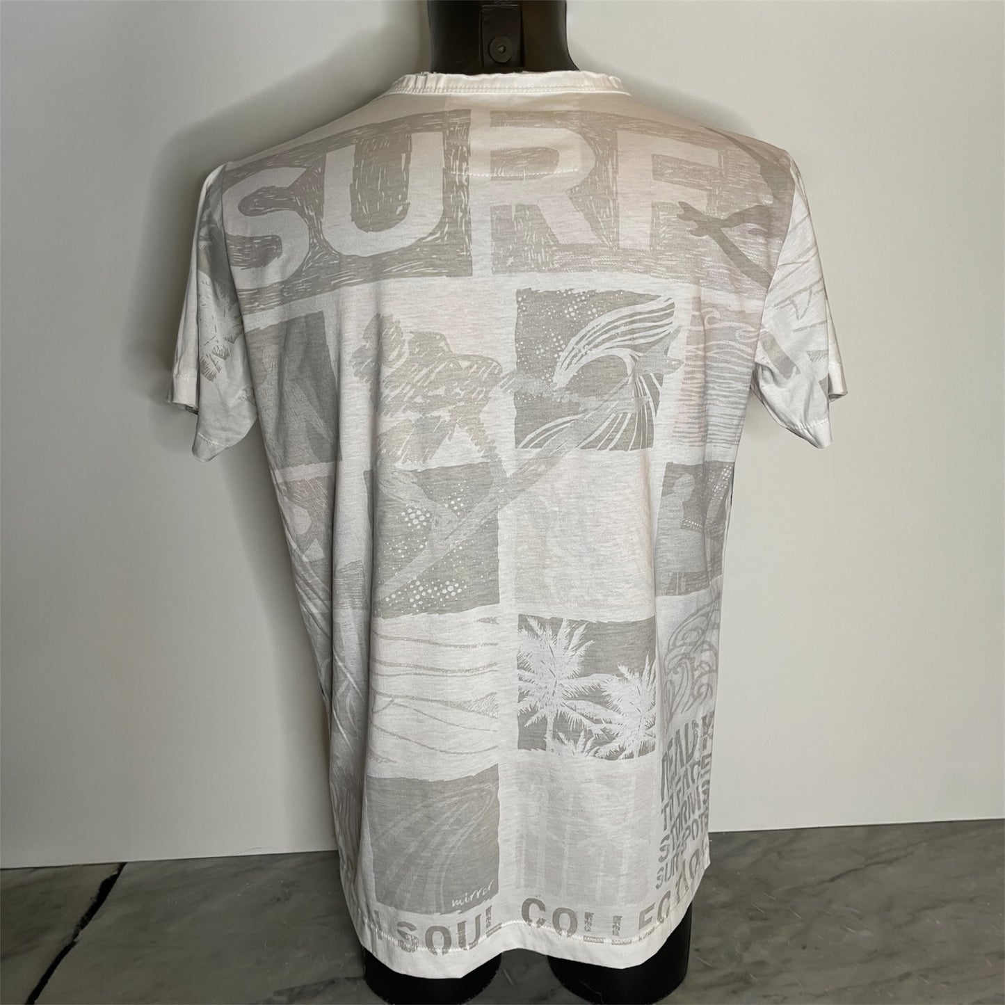 Maglietta unisex full-print “Ocean Grid” bianca, con mosaico grafico surf vintage in arancio e blu, back on model.