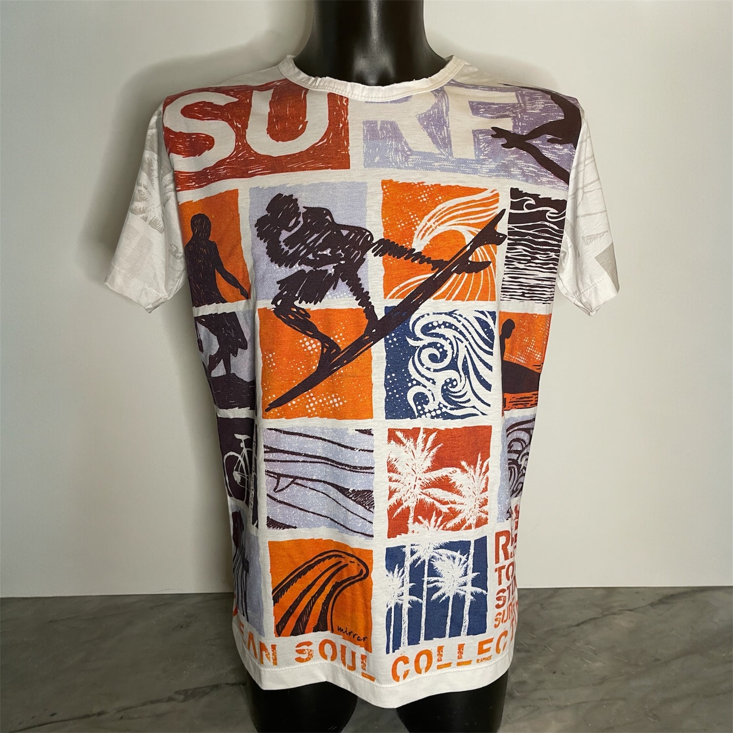 Maglietta unisex full-print “Ocean Grid” bianca, con mosaico grafico surf vintage in arancio e blu, on model.
