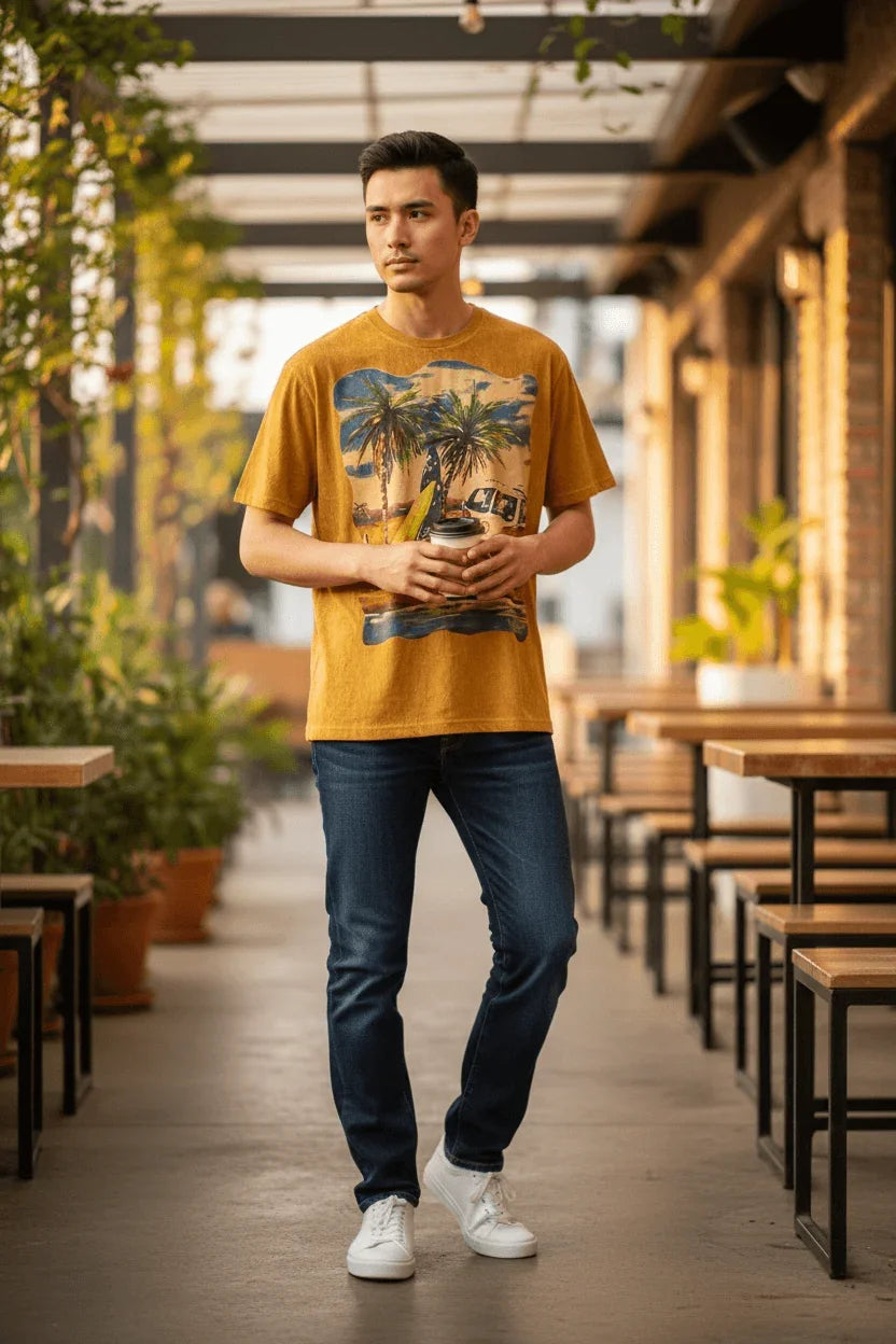 Modello indossa maglietta ql maglie surf camper ocra, jeans e sneakers bianche, ambiente casual
