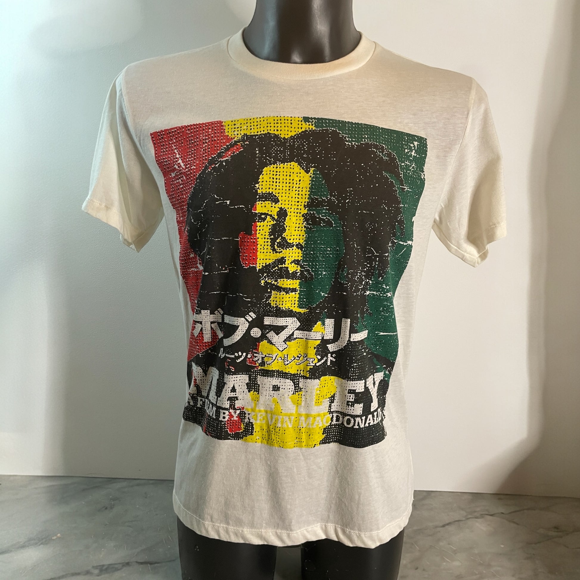 Maglietta bianca unisex in cotone con stampa del volto di Bob Marley ispirata al film documentario Marley (2012), grafica con colori rastafari e scritte giapponesi, model