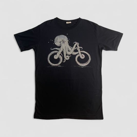 Maglietta nera unisex in cotone con stampa artistica di un polpo che pedala una bicicletta, stile creativo e alternativo.