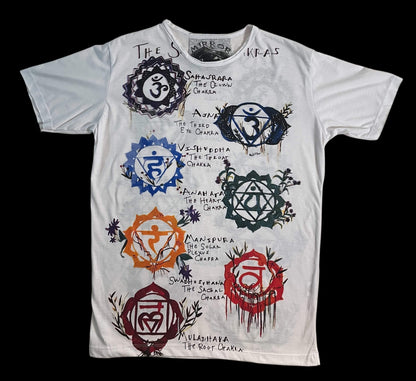 T-shirt bianca con illustrazione dei sette chakra e simboli energetici colorati, stile artistico.