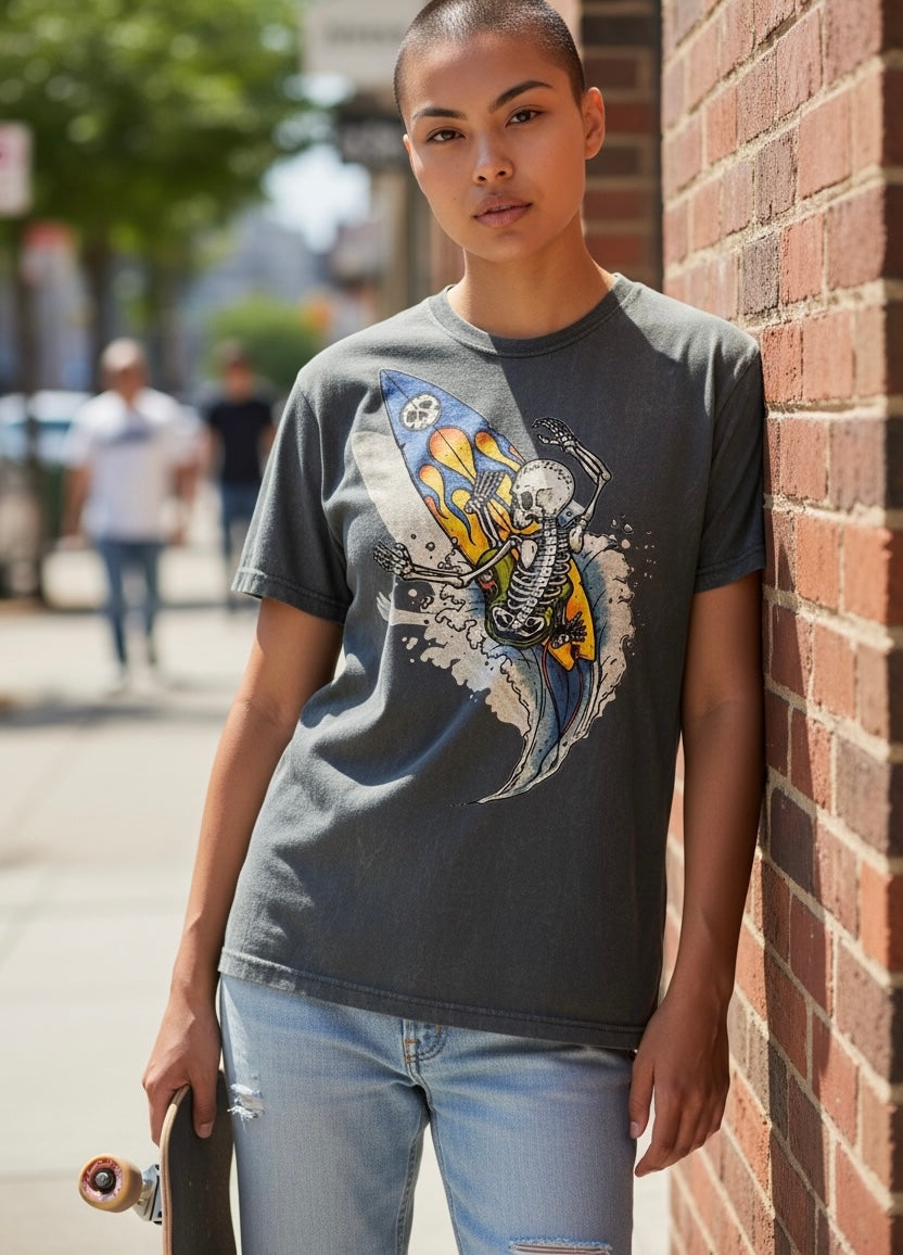 T-shirt vintage uomo con grafica di uno scheletro che surfa su una tavola con fiamme, sfondo effetto stone washed, street.