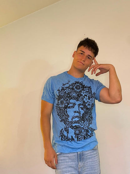 T-shirt azzurra floreale con stampa artistica, frase 'Back to basic', indossata.