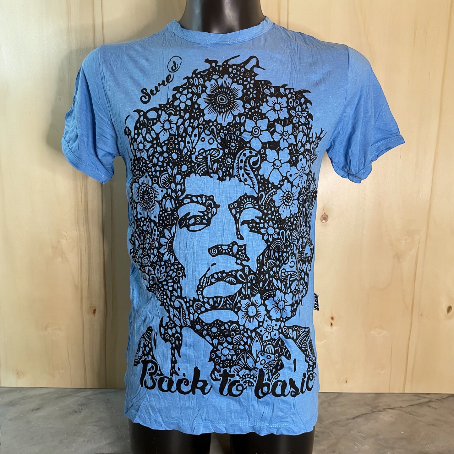 T-shirt blue unisex con ritratto floreale di Jimi Hendrix in bianco e nero e scritta “Back to Basic” by Sure, on model