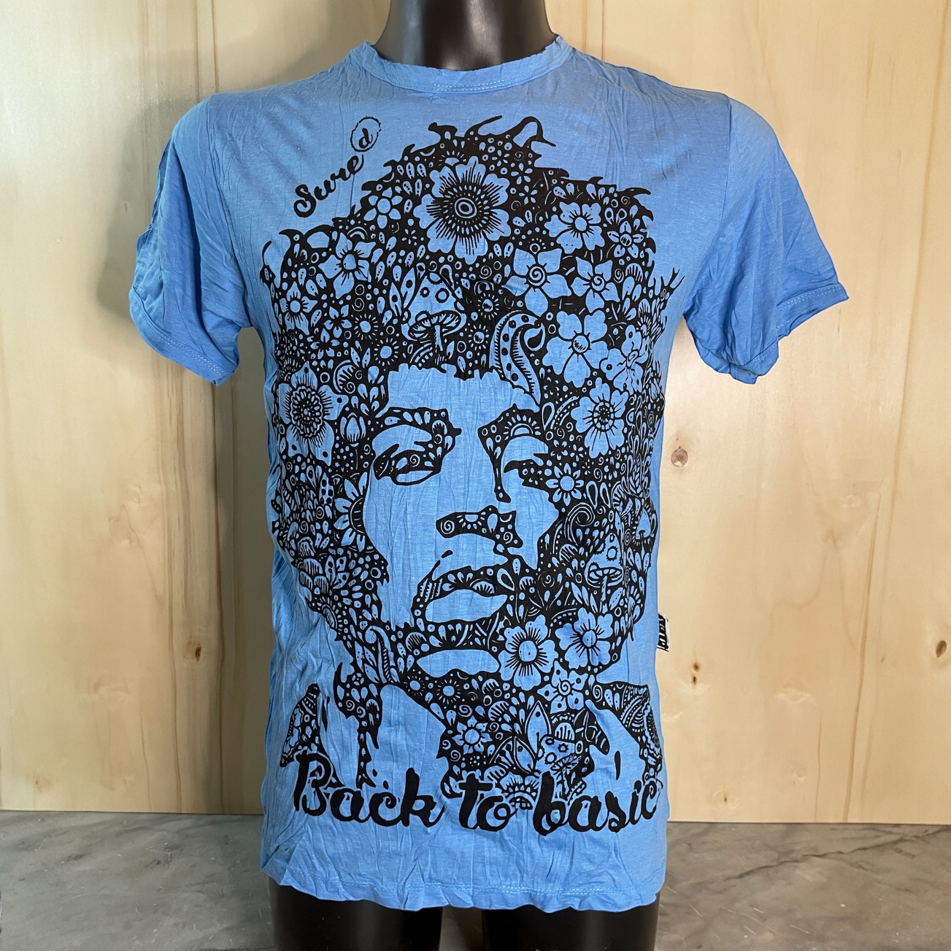T-shirt blue unisex con ritratto floreale di Jimi Hendrix in bianco e nero e scritta “Back to Basic” by Sure, on model