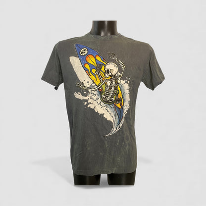 T-shirt vintage uomo con grafica di uno scheletro che surfa su una tavola con fiamme, sfondo effetto stone washed, uomo.